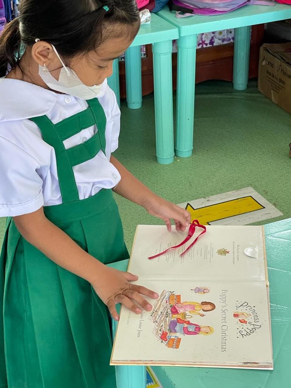 A young girl reading a book whilst wearing a mask during the COVID-19 pandemic